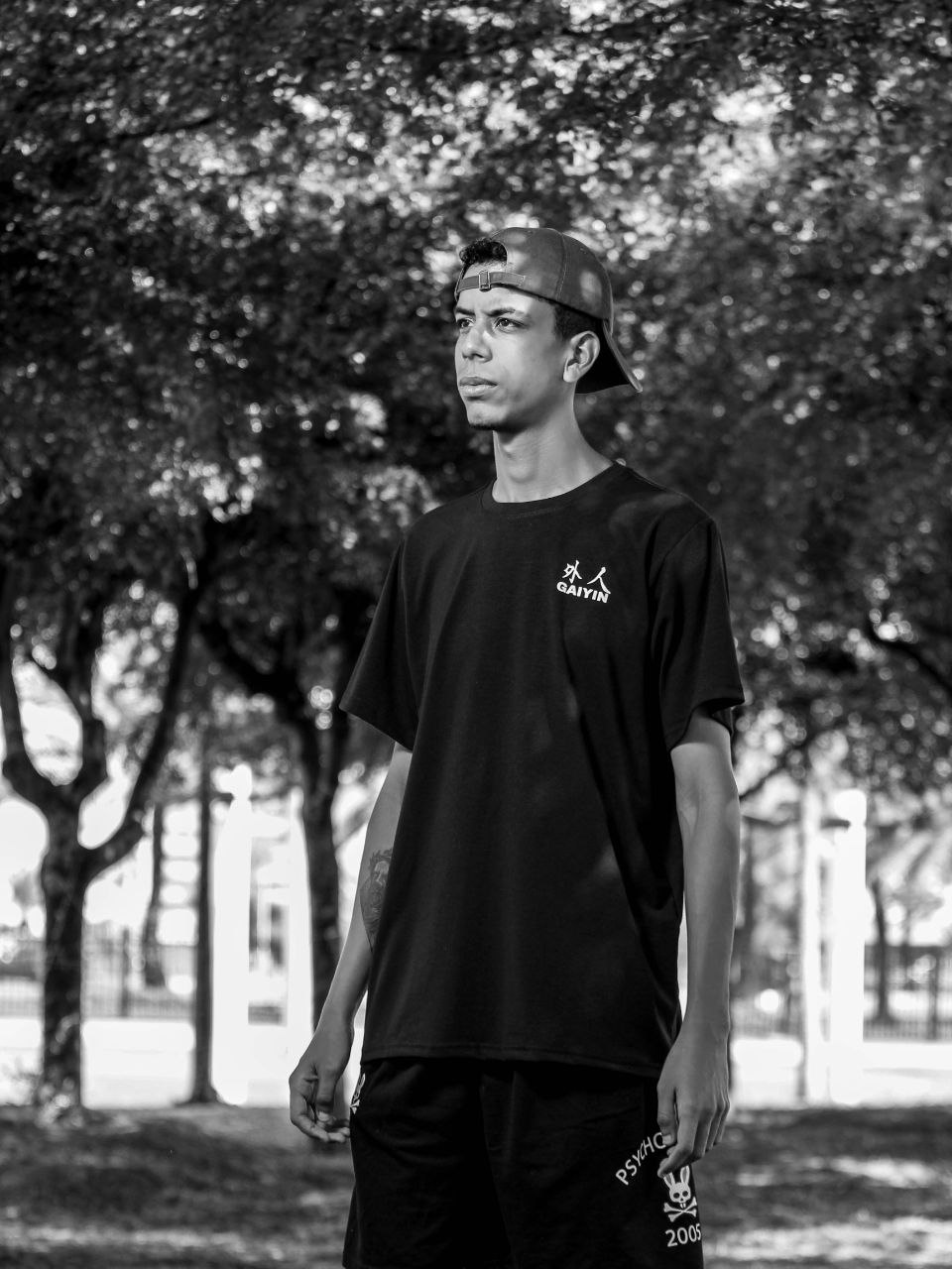 Homem negro com moletom bege mexendo no celular e sorrindo